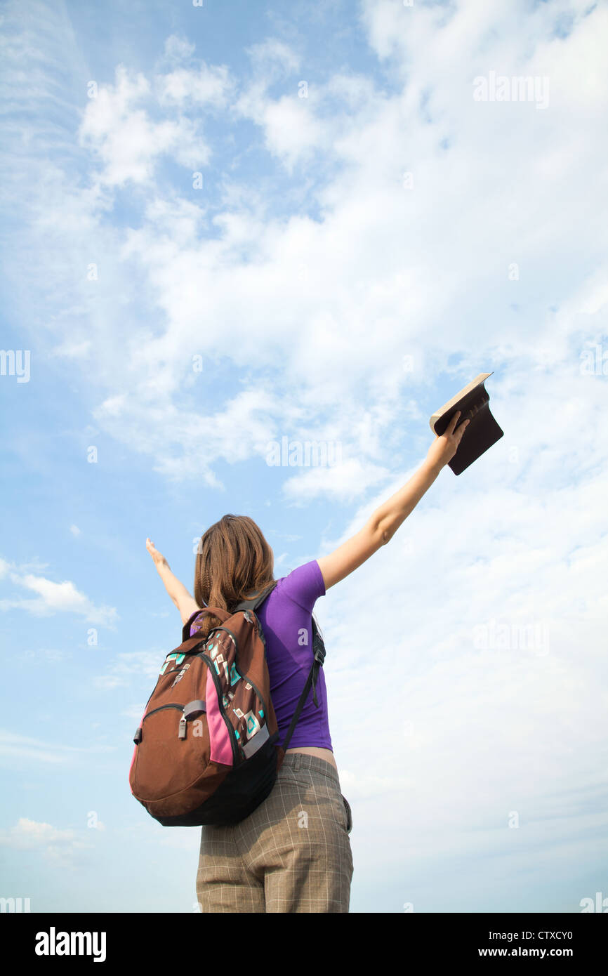 Teenage girl staying with raised hands against blue sky Stock Photo - Alamy
