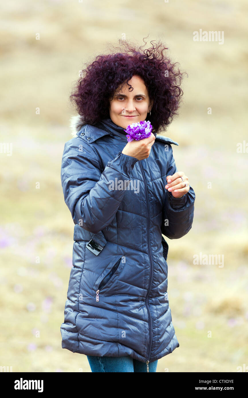 Candid portrait of a curly redhead woman picking crocus flowers in a ...