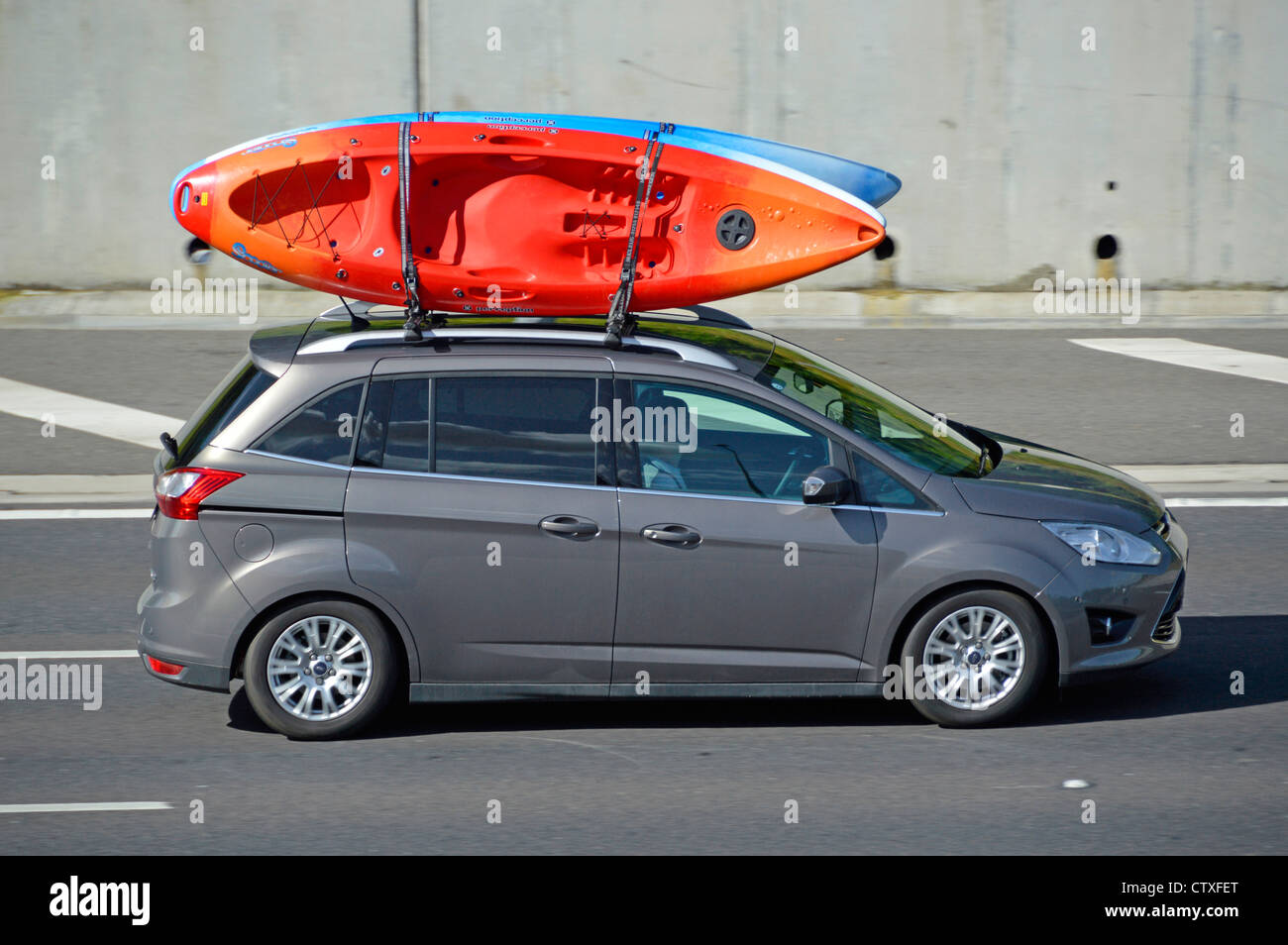 Car driving along with transporting canoe kayaks on roof rack Stock Photo