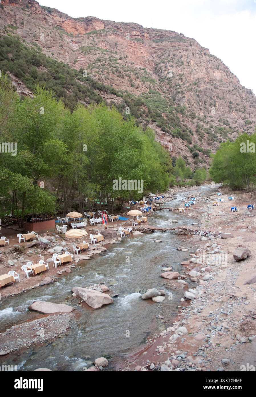 dining tables and chairs laid out along a valley river in the high atlas mountains morocco Stock Photo