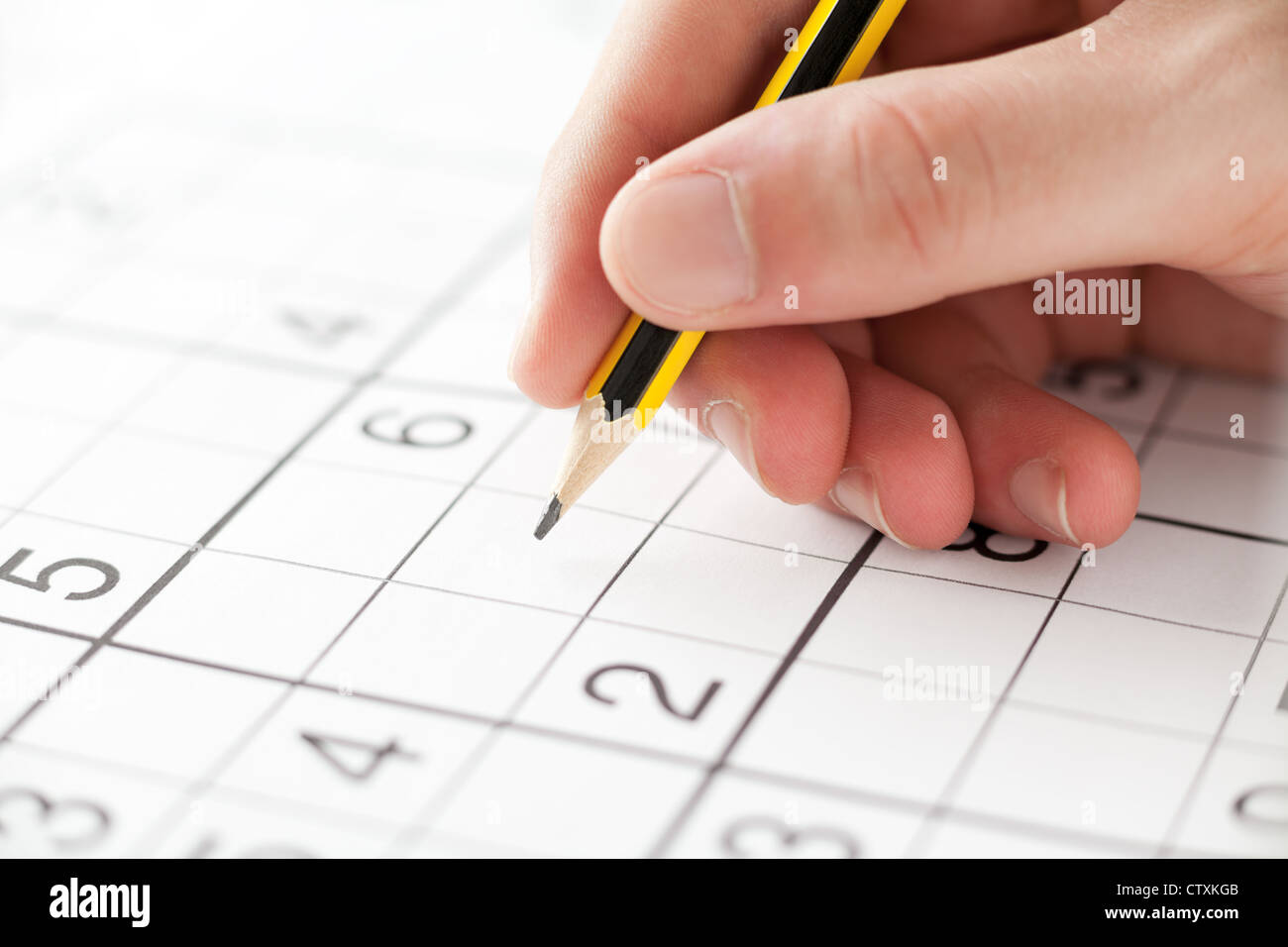 Hand Holding a Pencil Playing Sudoku Stock Photo