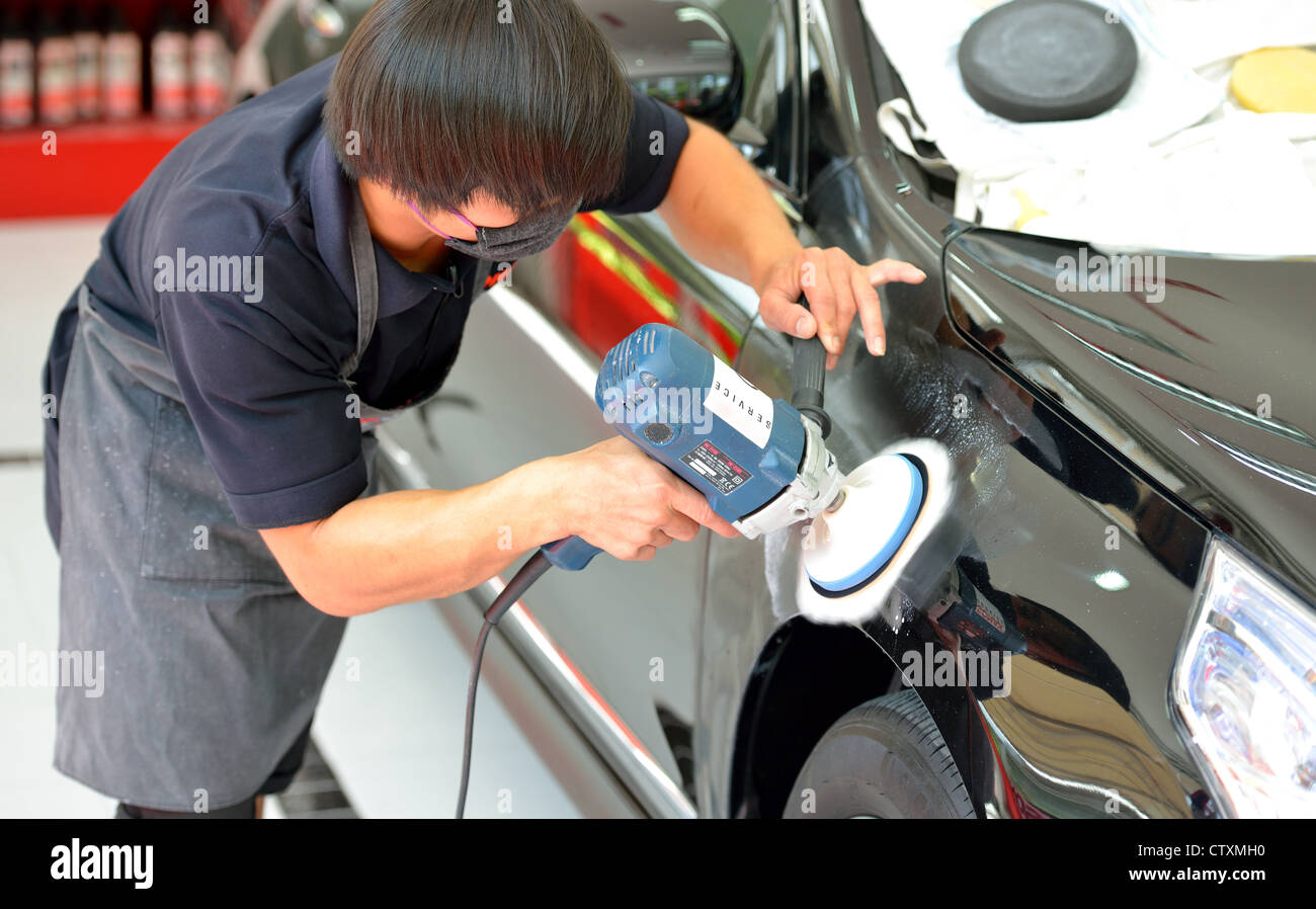 The man is polishing the black car with polish machine. Stock Photo