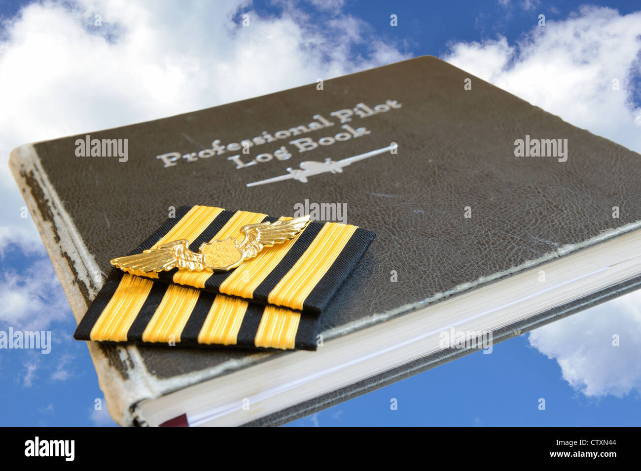 Four bar sign and golden metal wing of pilot put on the old pilot log book. Stock Photo