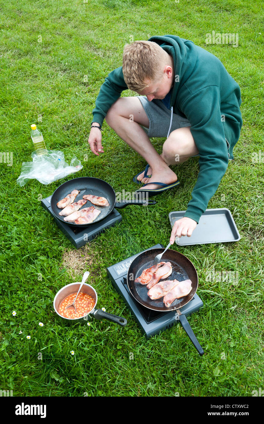 https://c8.alamy.com/comp/CTXWC2/man-cooking-bacon-in-frying-pans-outdoors-while-camping-uk-CTXWC2.jpg