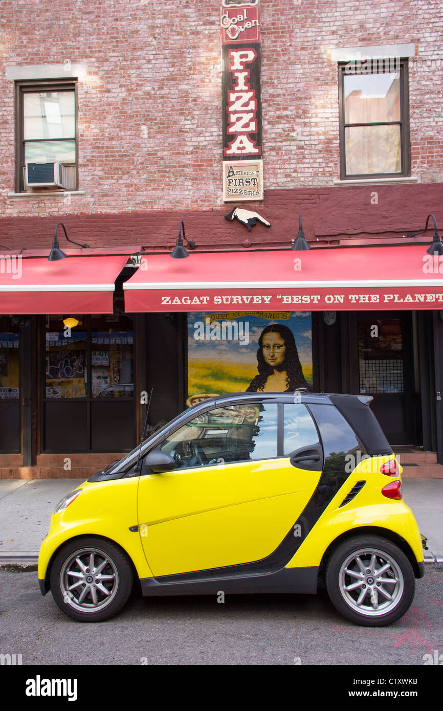 A bright yellow smart car parked in front of Lombardi's Pizzaria in Nolita Stock Photo