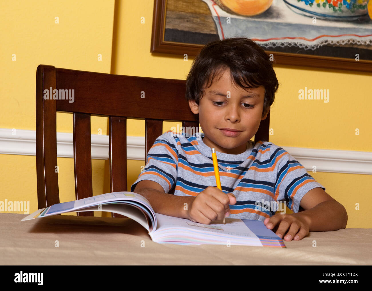 Mexican-American 8 year old elementary school age boy does school second grade homework at home writing, using pencil Stock Photo