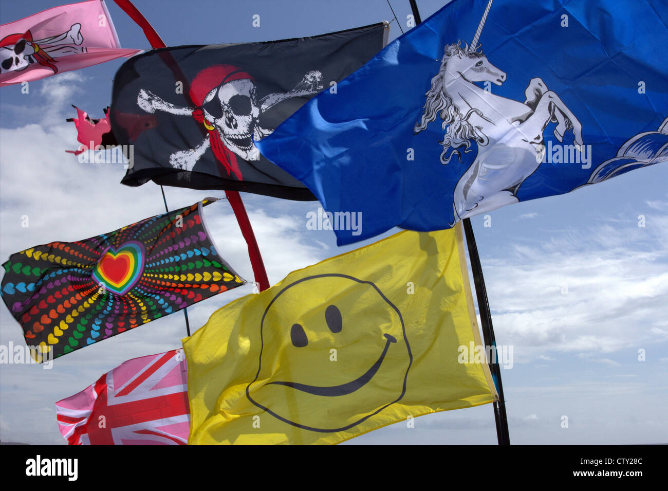 brightly colored flags with various psychedelic designs blowing in the wind on a sunny day Stock Photo
