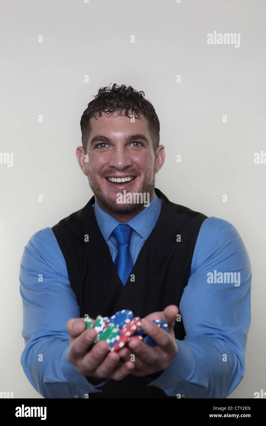 handsome man holding a lot of poker chips in two hands looking very