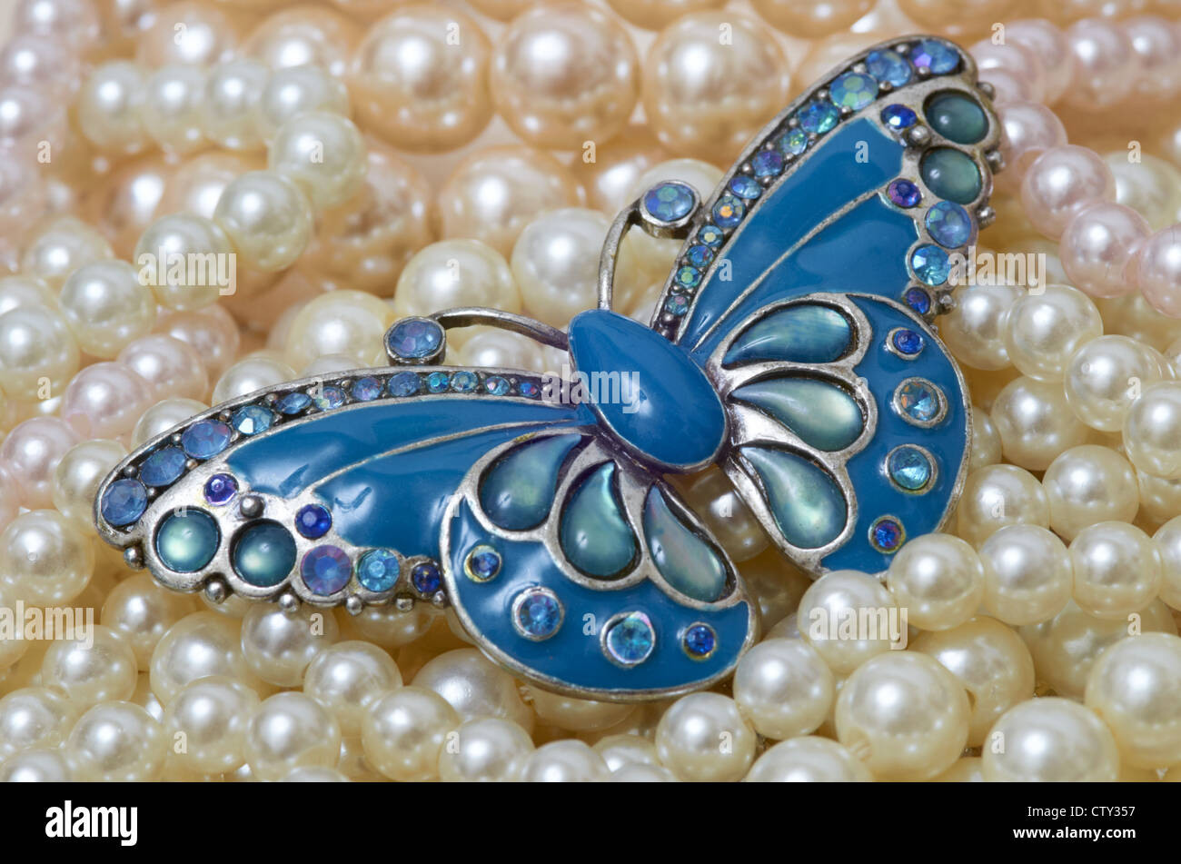 Butterfly brooch on a bed of pearls Stock Photo