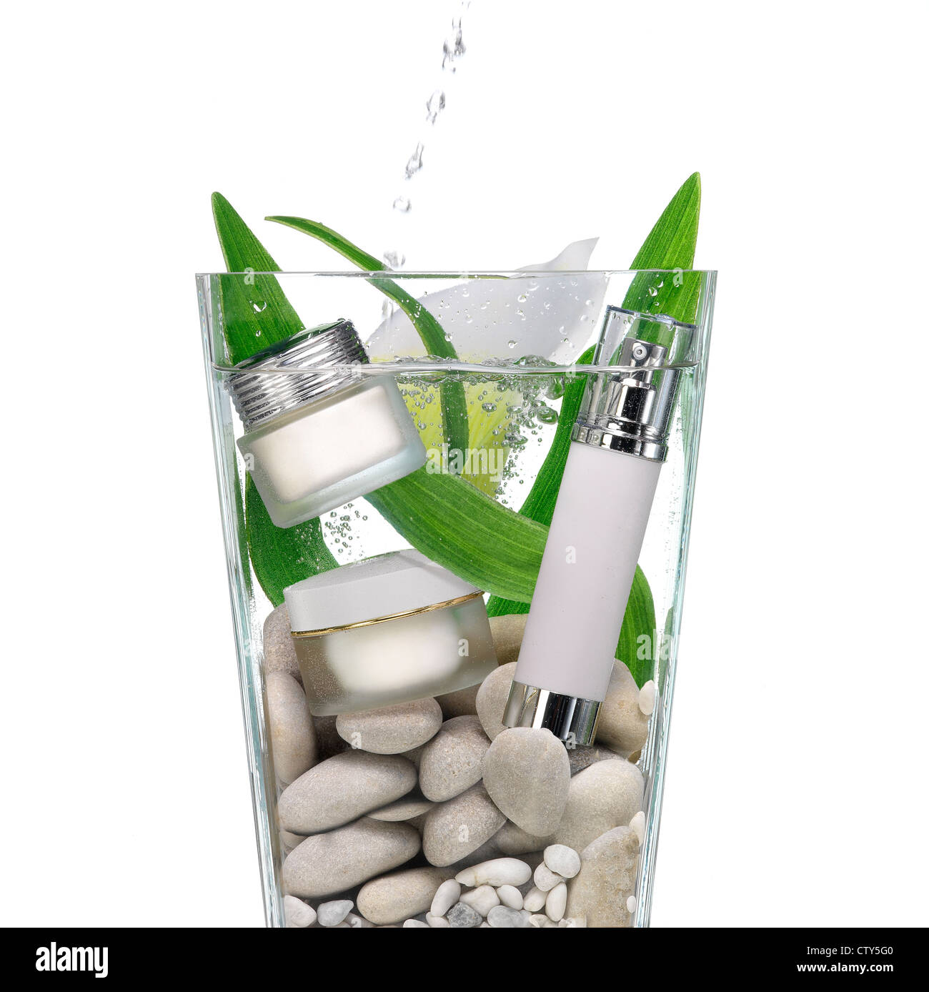 Cosmetics in a vase of water with stones and green leaves Stock Photo