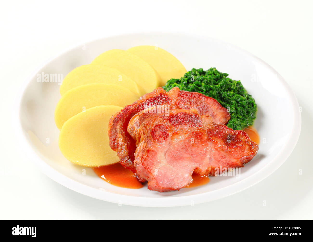 Pan roasted smoked pork neck with potato dumplings and spinach Stock Photo