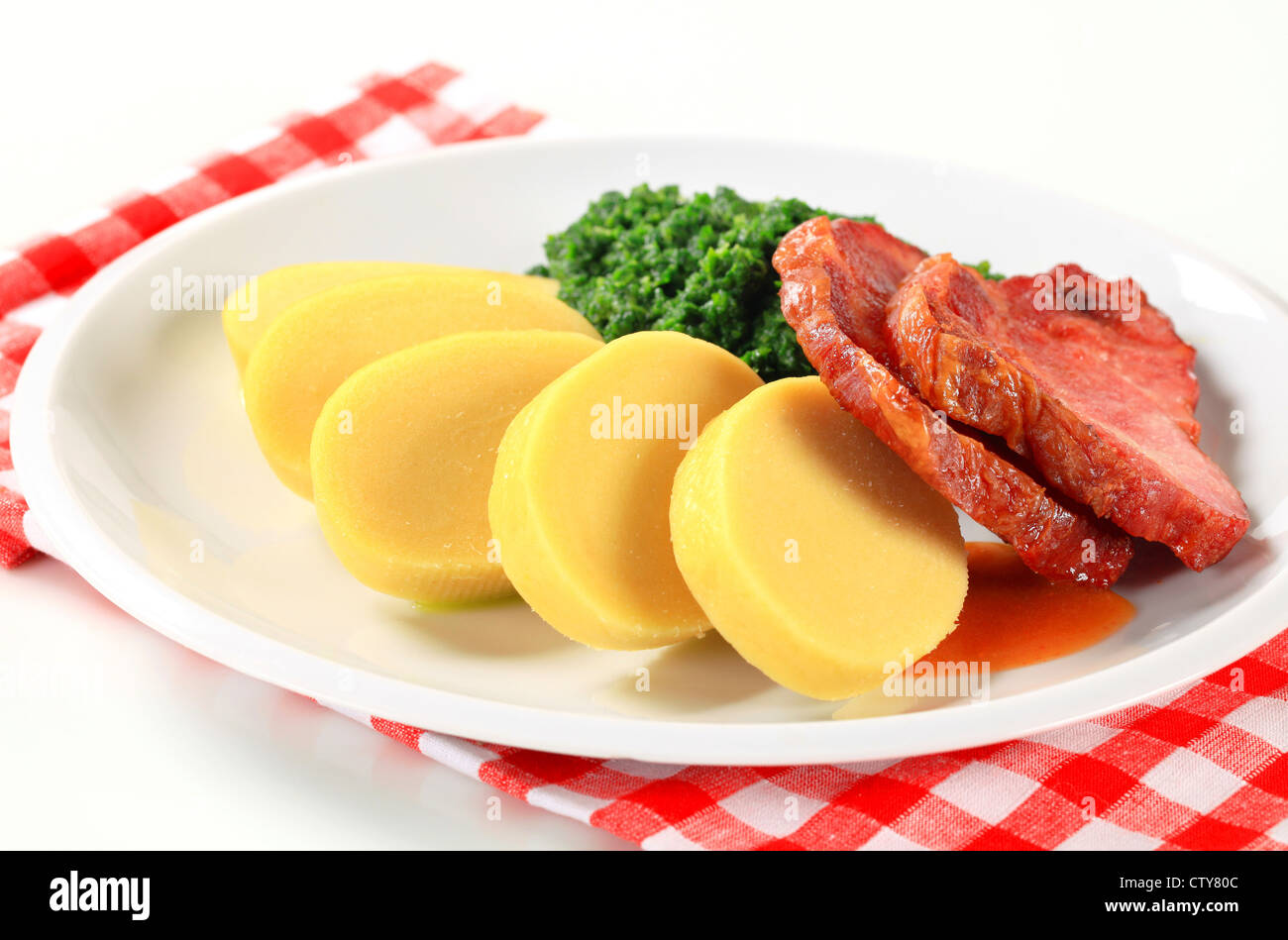 Pan roasted smoked pork neck with potato dumplings and spinach Stock Photo