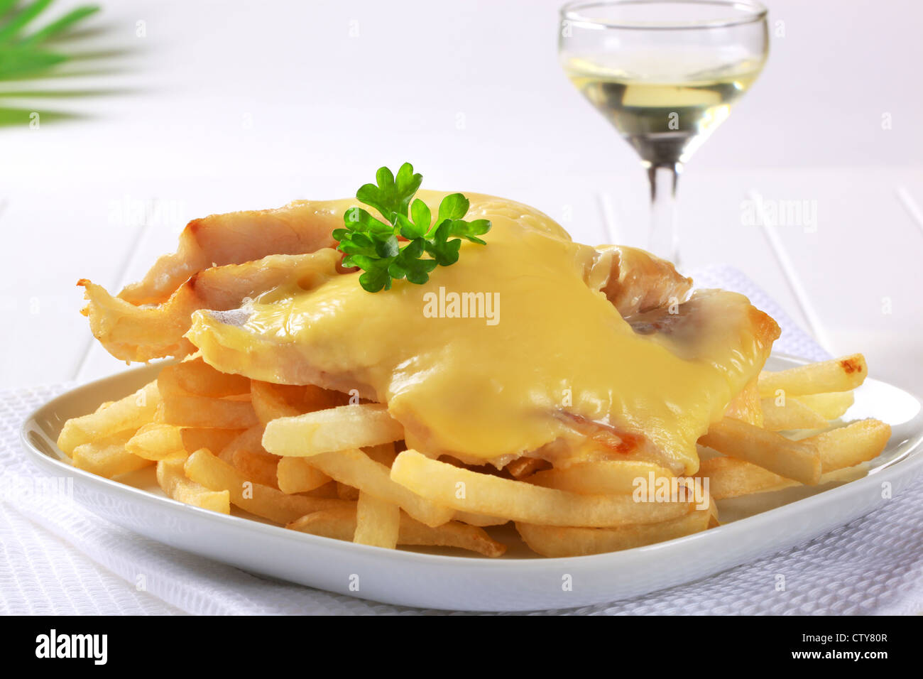 Cheese topped fish fillets served with French fries Stock Photo