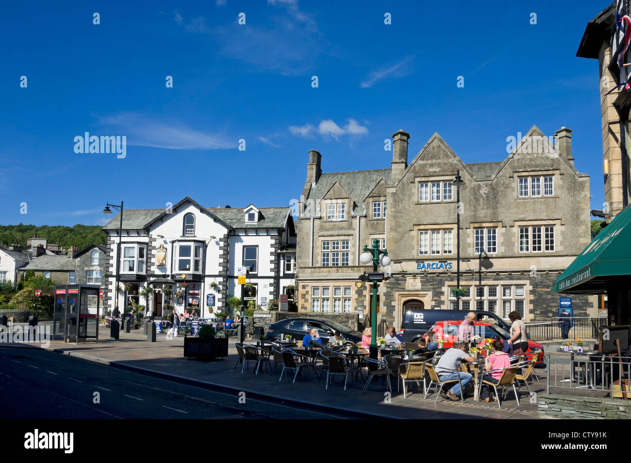 People visitors tourists sitting sat outside cafe bar in the town centre in summer Windermere Cumbria England UK United Kingdom GB Great Britain Stock Photo