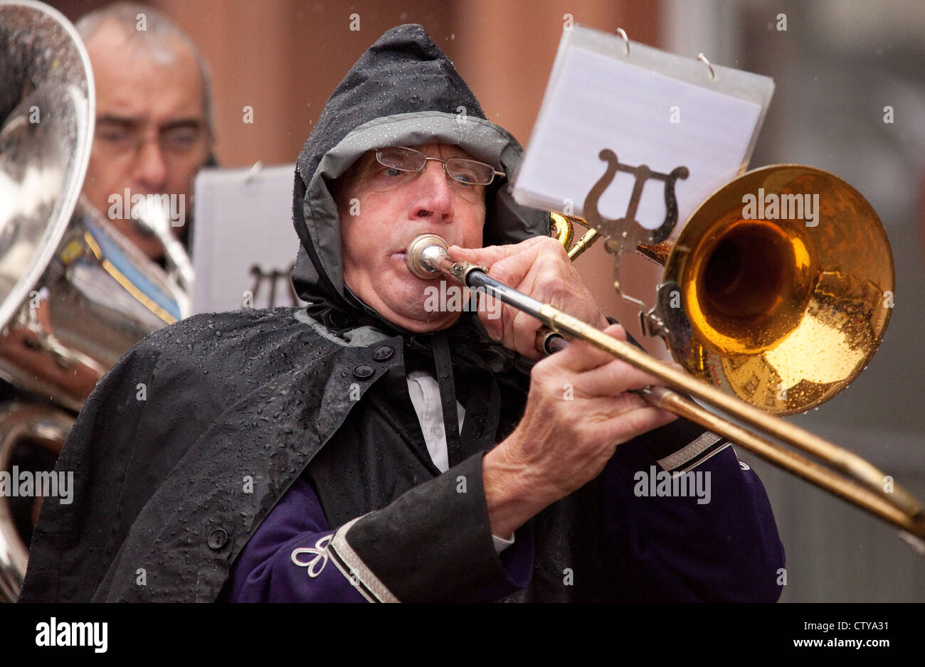 Visually impaired rain on glasses of musician trombone player in brass band trying to read music Stock Photo