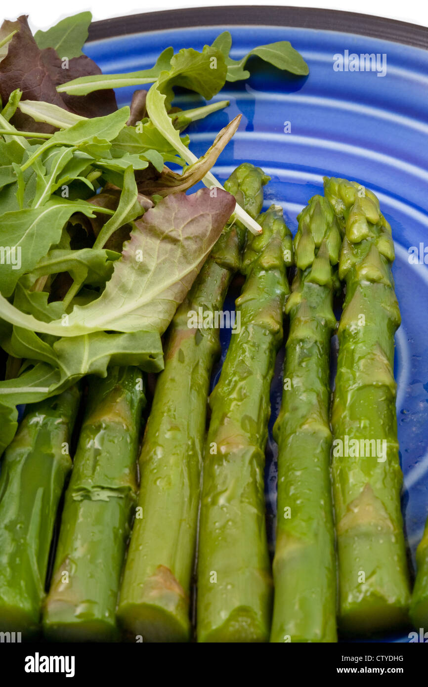 boiled green asparagus with salad mix on blue plate Stock Photo