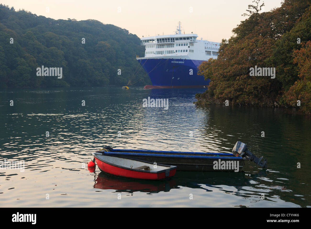 Small boats moored and large cargo ship laid up in deep Fal River during global recession. Falmouth, Cornwall, England, UK Stock Photo