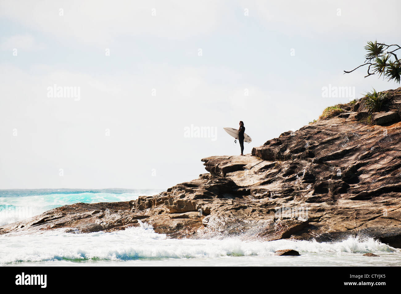 A surfer standing on the headland at Cylinder Beach on North Stradbroke Island in Queensland in Australia. Stock Photo