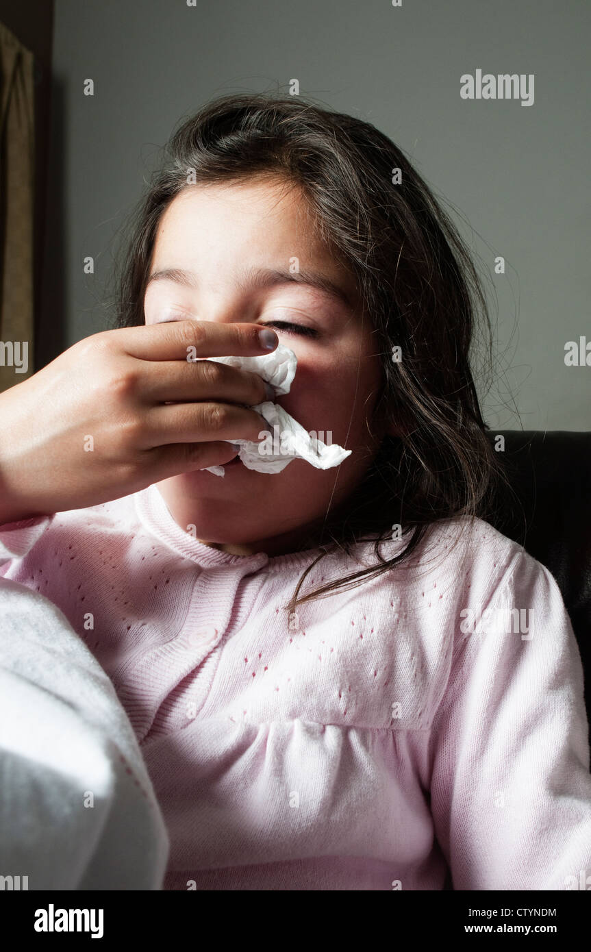 Child with a flue symptoms sneezes in napkin Stock Photo