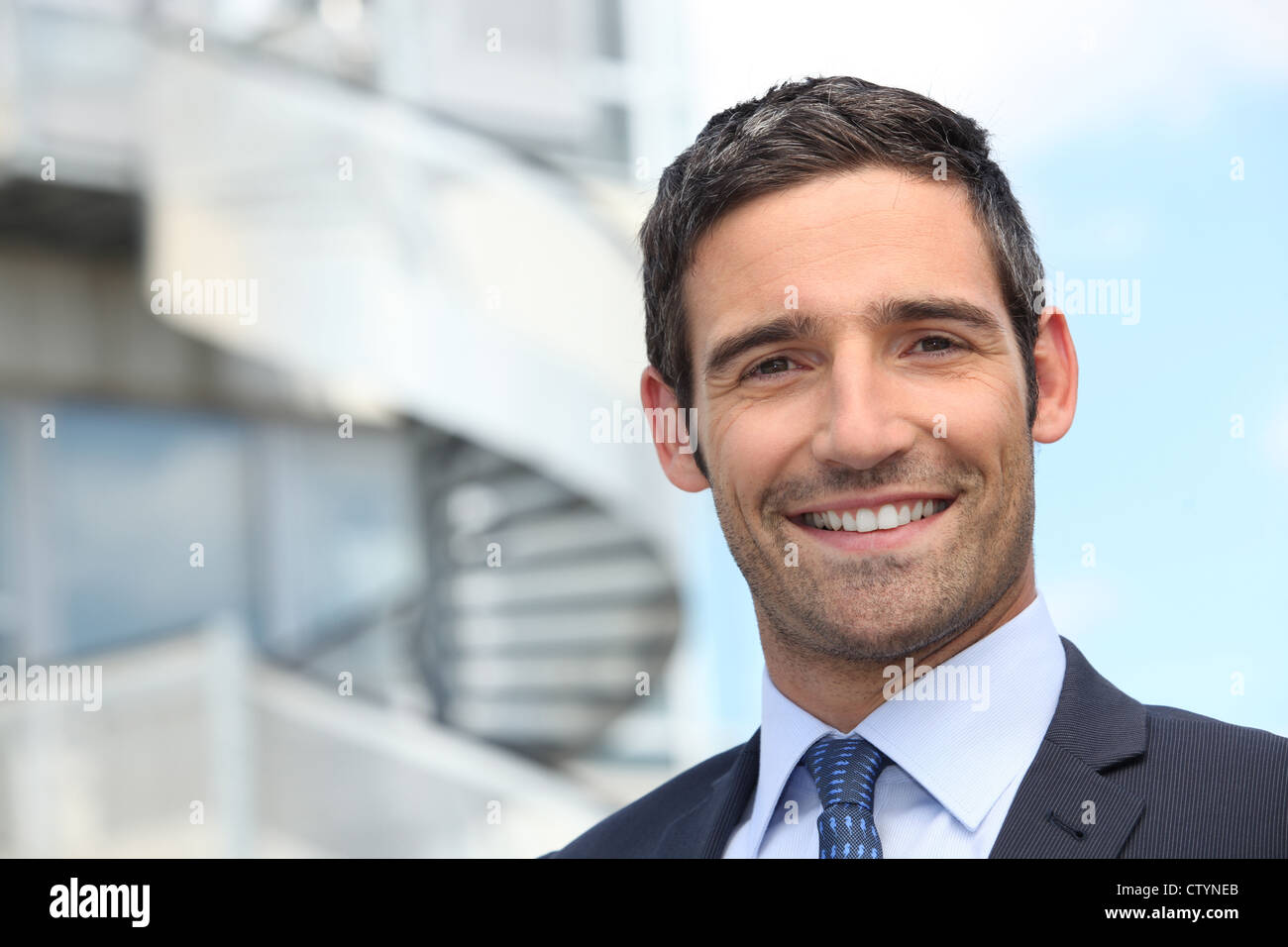 Smiling business man standing outside office building Stock Photo - Alamy