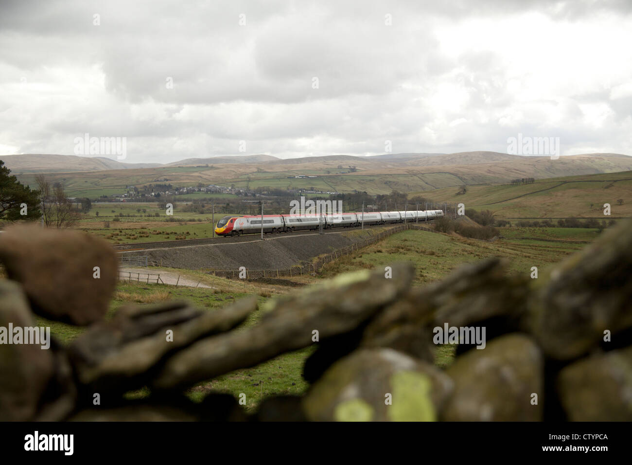Virgin trains Pendolino train climbs the Cumbria/Westmoreland Shap hills at Greenholme, Tebay with a Glasgow bound train. Stock Photo