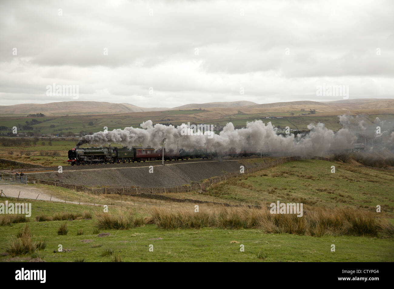 Steam locomotive 70013 'Oliver Cromwell' takes a Cumbrian Mountain Express train over Shap at Greenholme, Cumbria, England. Stock Photo
