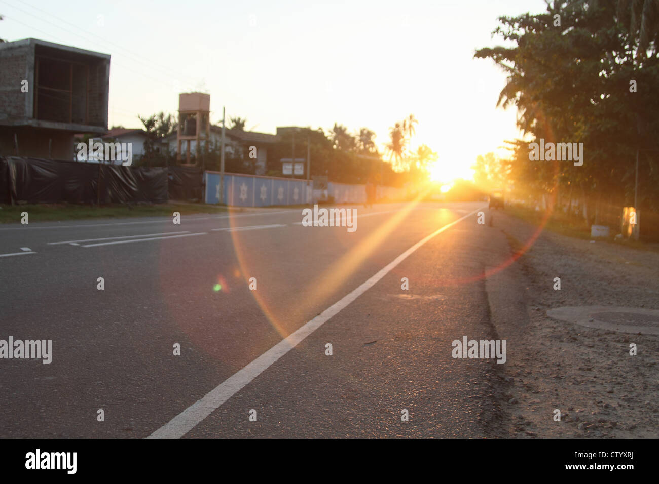 Sun shining on rural road Stock Photo