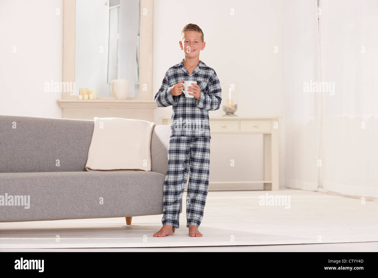 Boy in pajamas with mug in living room Stock Photo Alamy