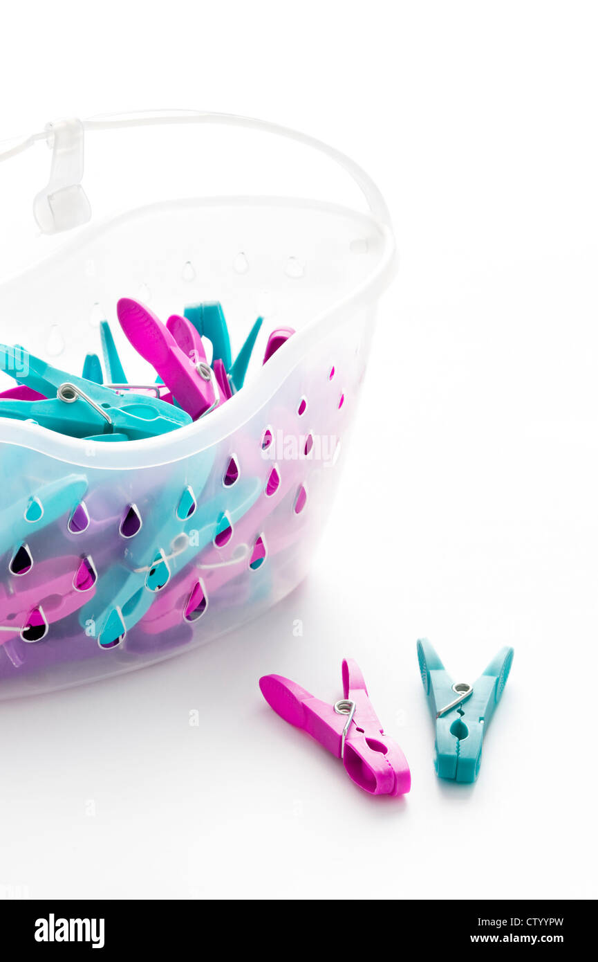 coloured or colored plastic clothes pegs and basket on a white background Stock Photo
