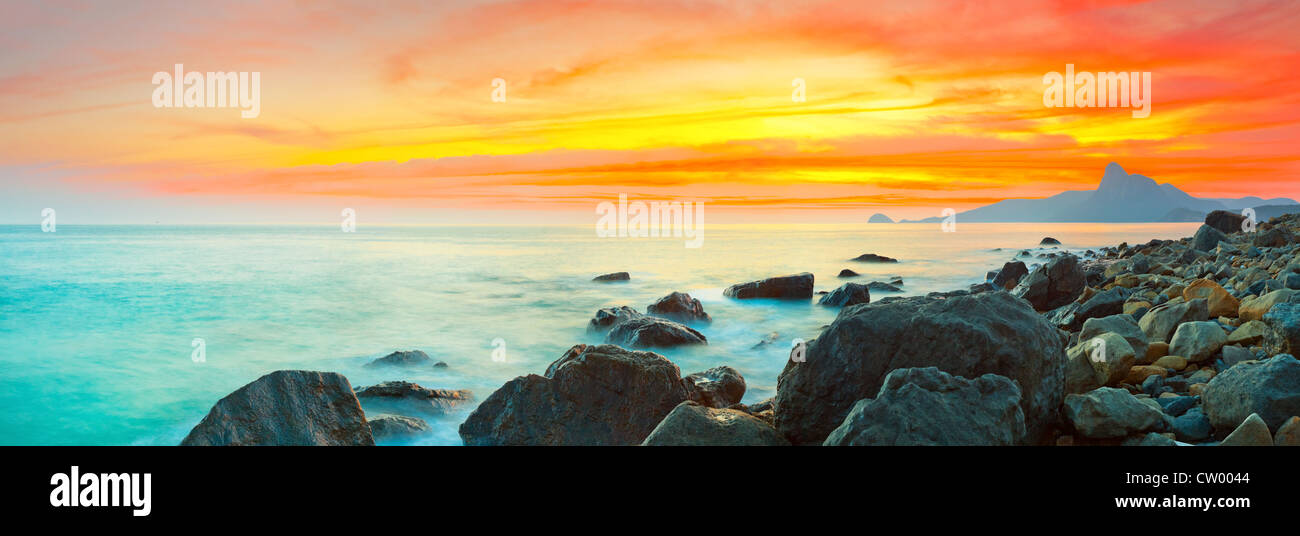 Sunset over the sea. Stone on the foreground. Panorama Stock Photo