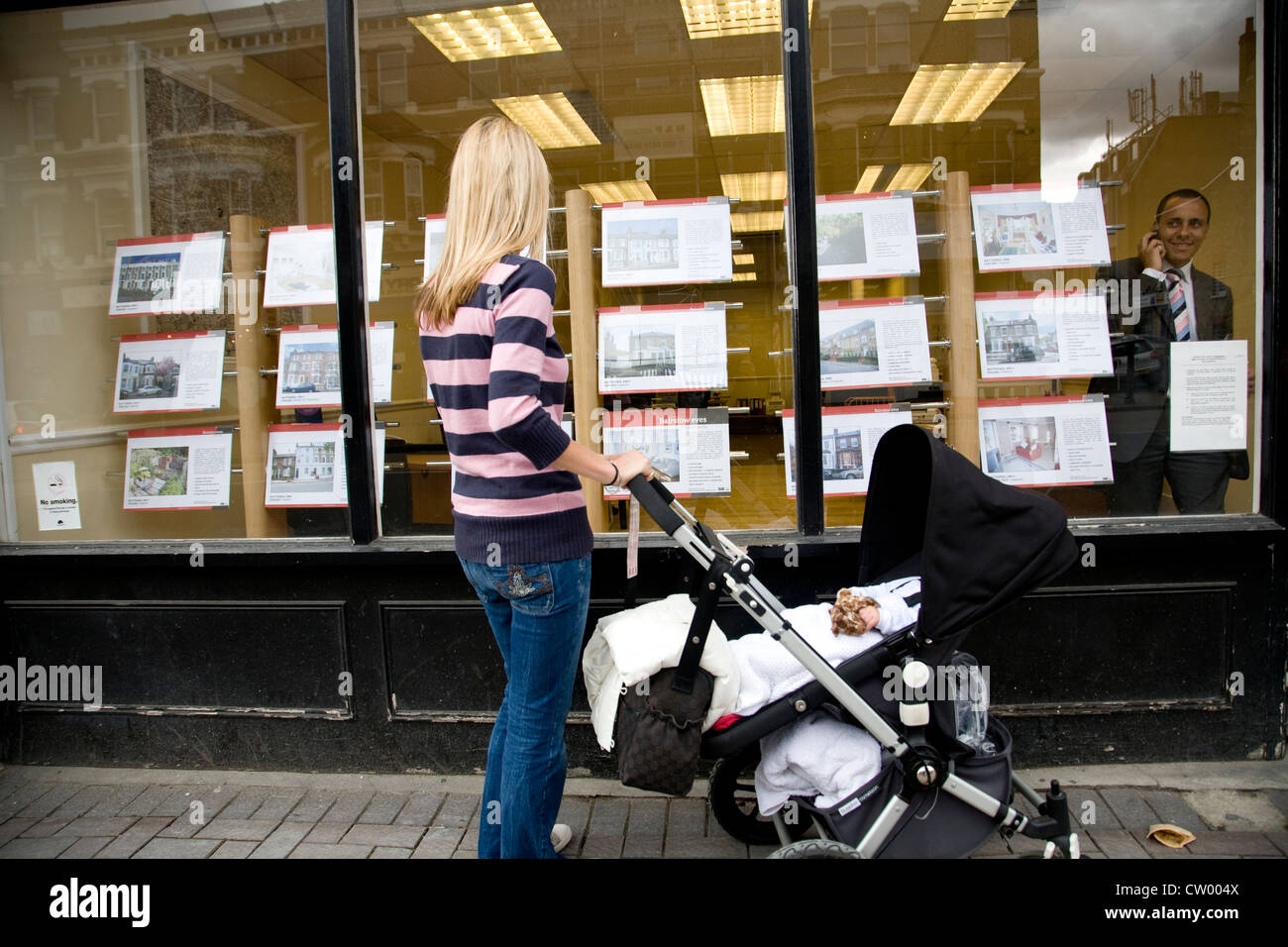 Woman and child look at properties advertised for sale in an Estate Agents window, London, UK. Photo:Jeff Gilbert Stock Photo