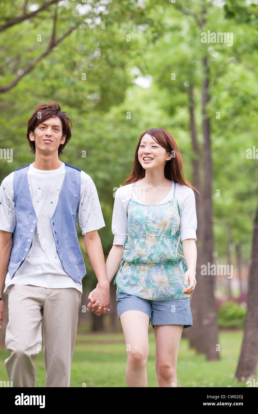 Young couple walking holding hands Stock Photo - Alamy