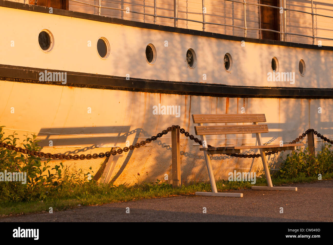 A bench by an old ship at sunset Stock Photo
