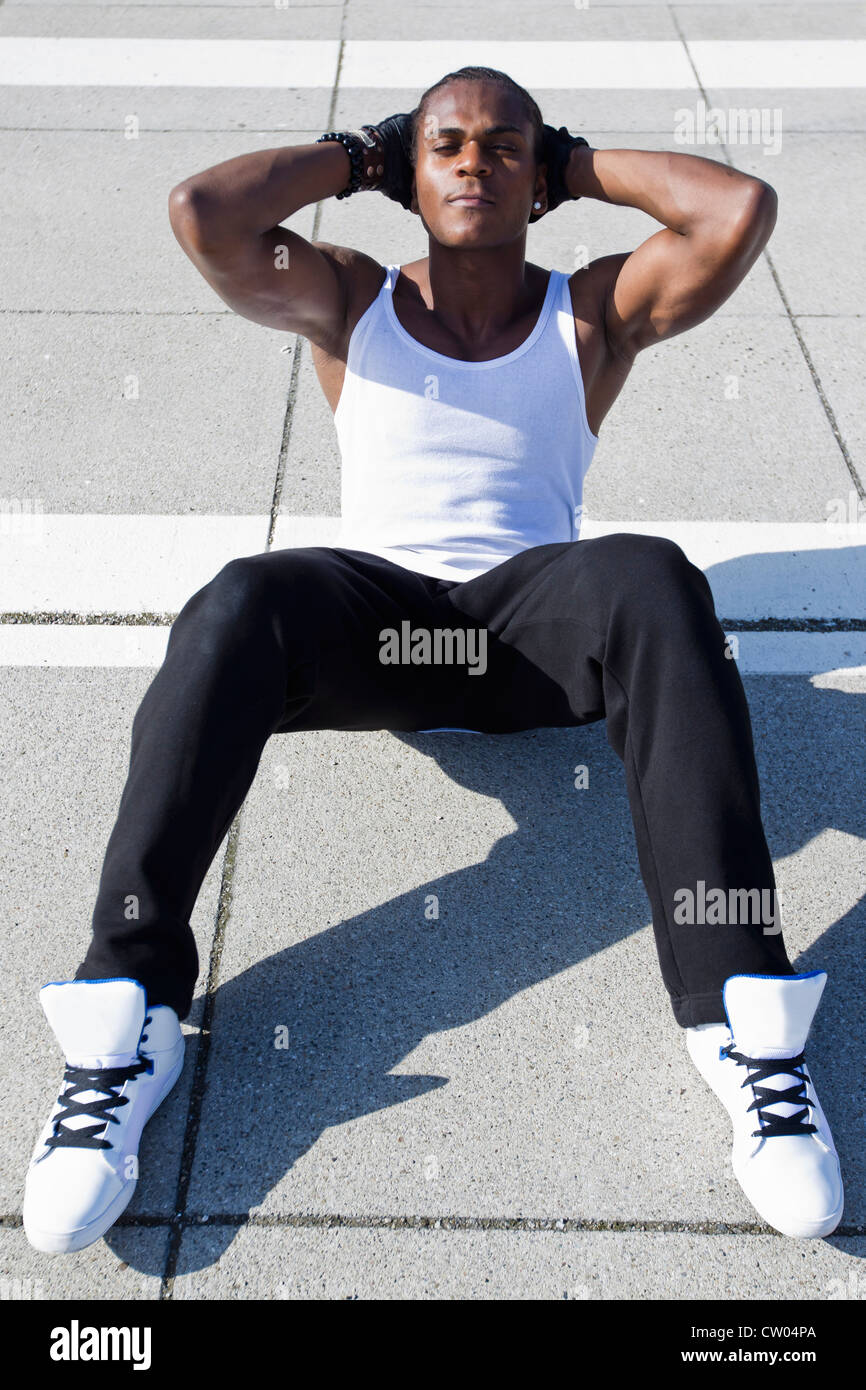 Athlete doing sit ups on sidewalk Stock Photo