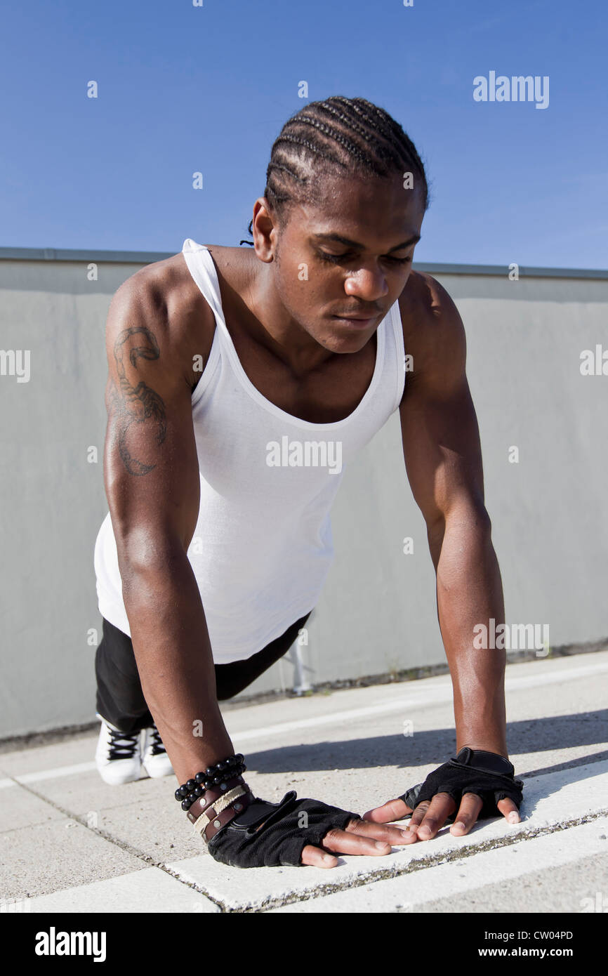 Athlete doing push ups on sidewalk Stock Photo