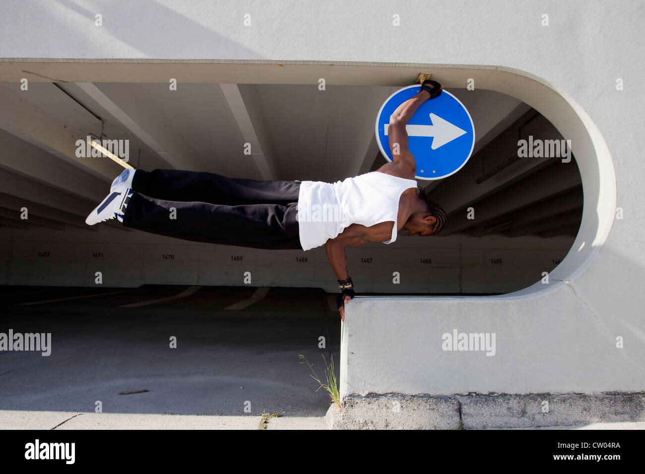 Man balancing on ledge on city street Stock Photo