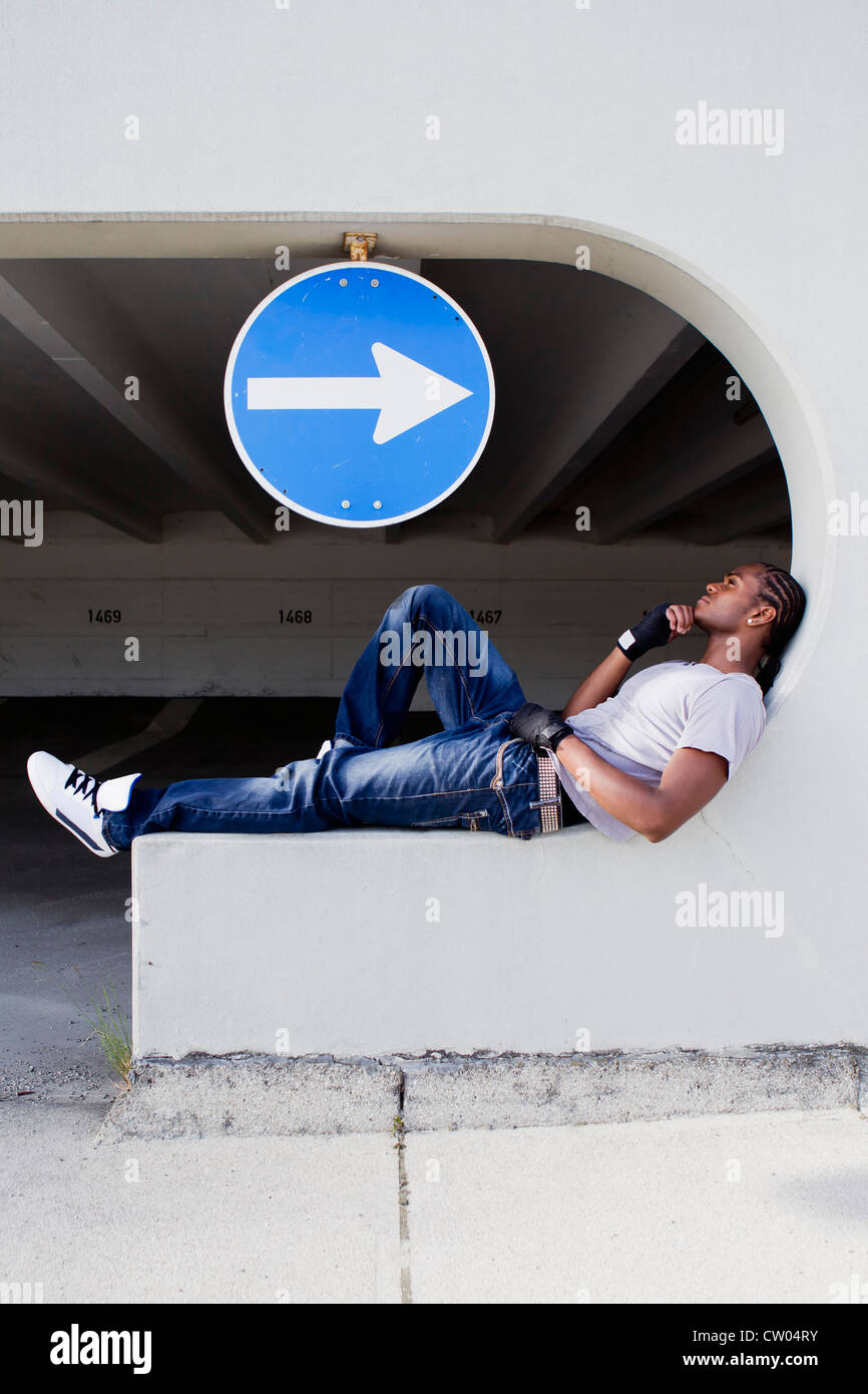 Man sitting on ledge on city street Stock Photo