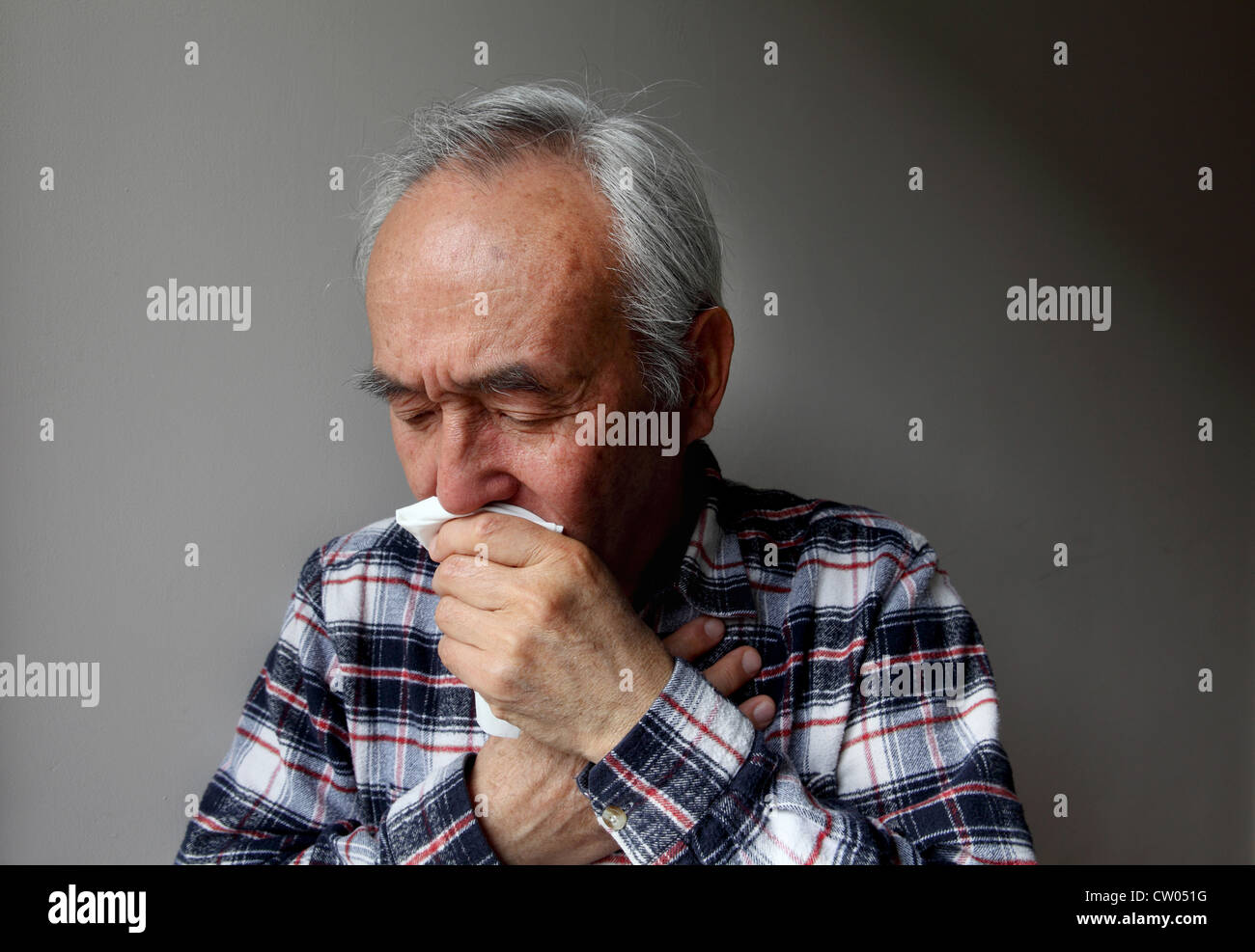 Older man coughing into napkin Stock Photo