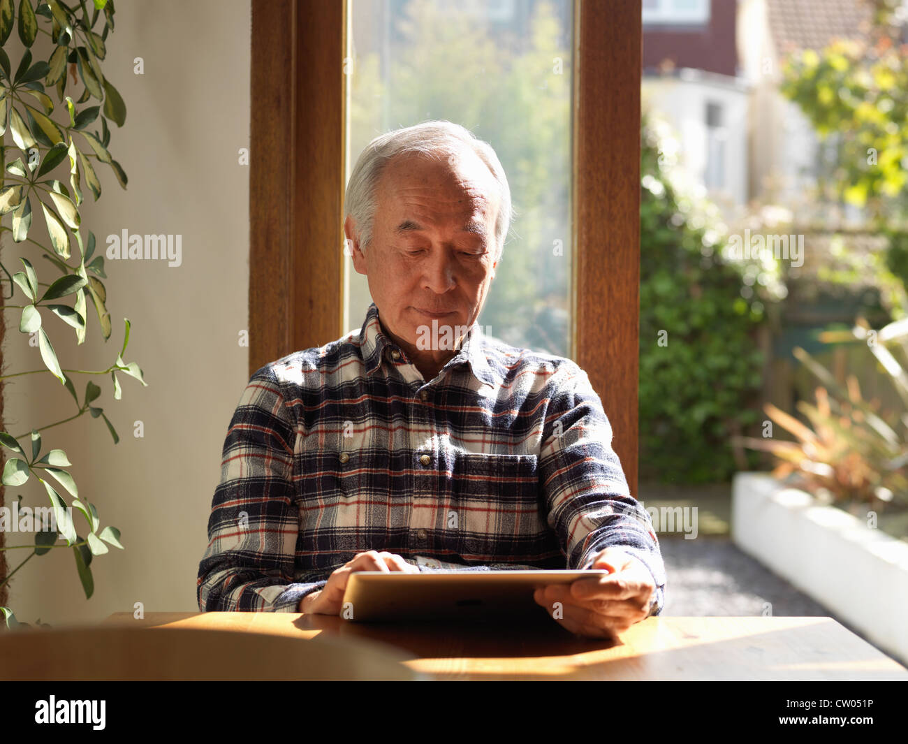 Older man using tablet computer at table Stock Photo