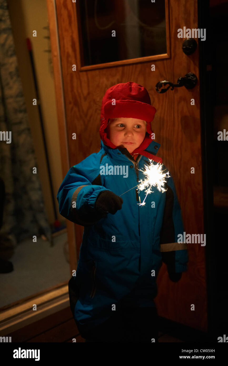 Boy playing with sparkler outdoors Stock Photo