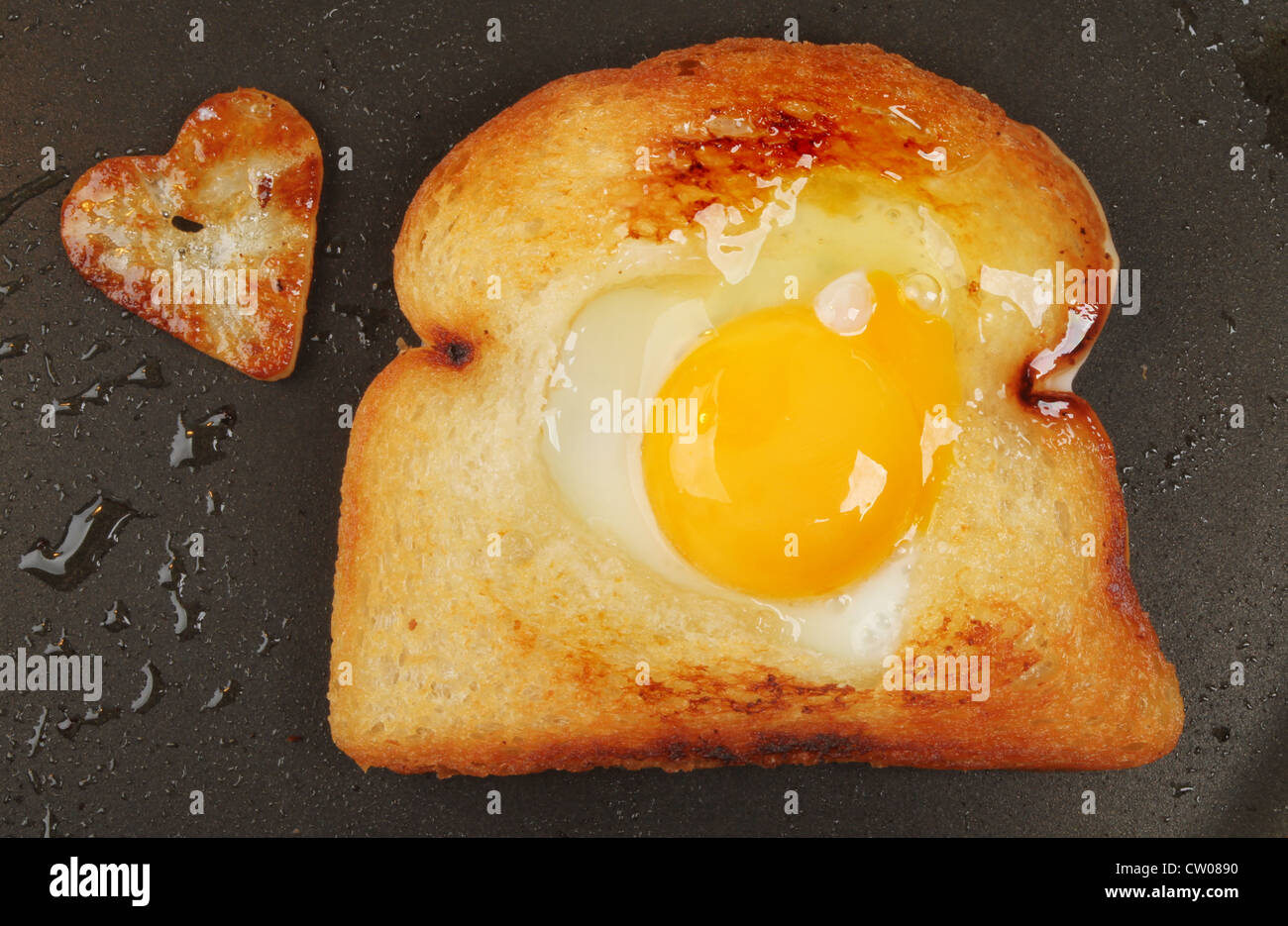 Fried bread with an egg and a heart shaped fried potato in a frying pan Stock Photo