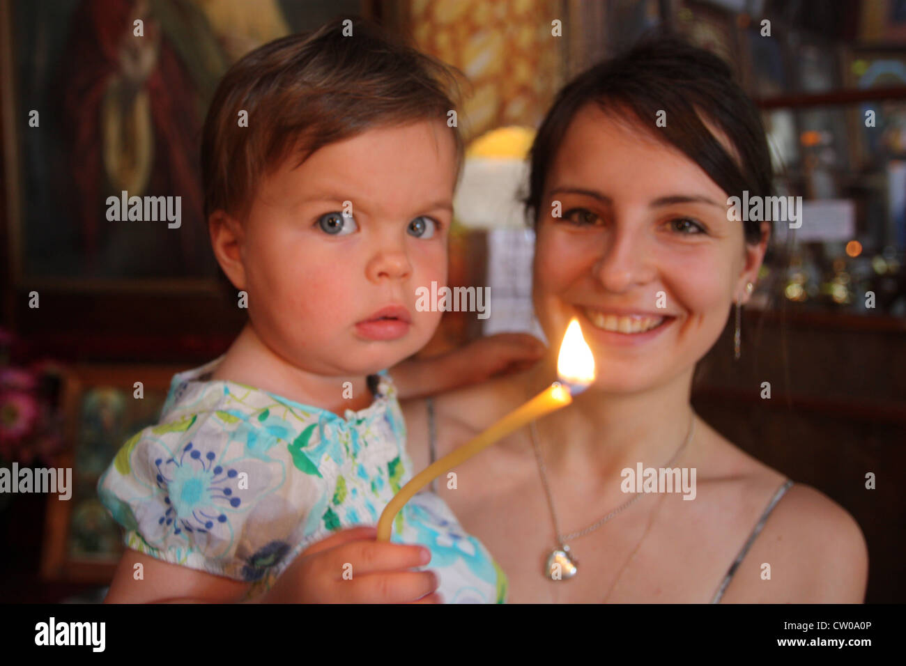 Mother and baby daughter in Bulgarian church with candle Stock Photo