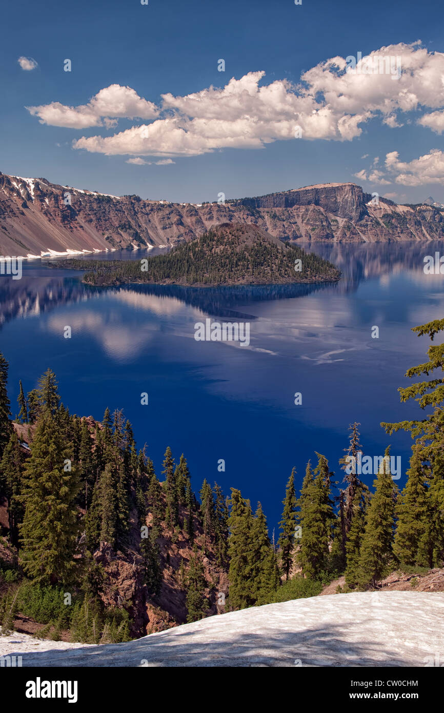 Afternoon clouds and Wizard Island reflect in the calm water of Oregon’s Crater Lake National Park. Stock Photo