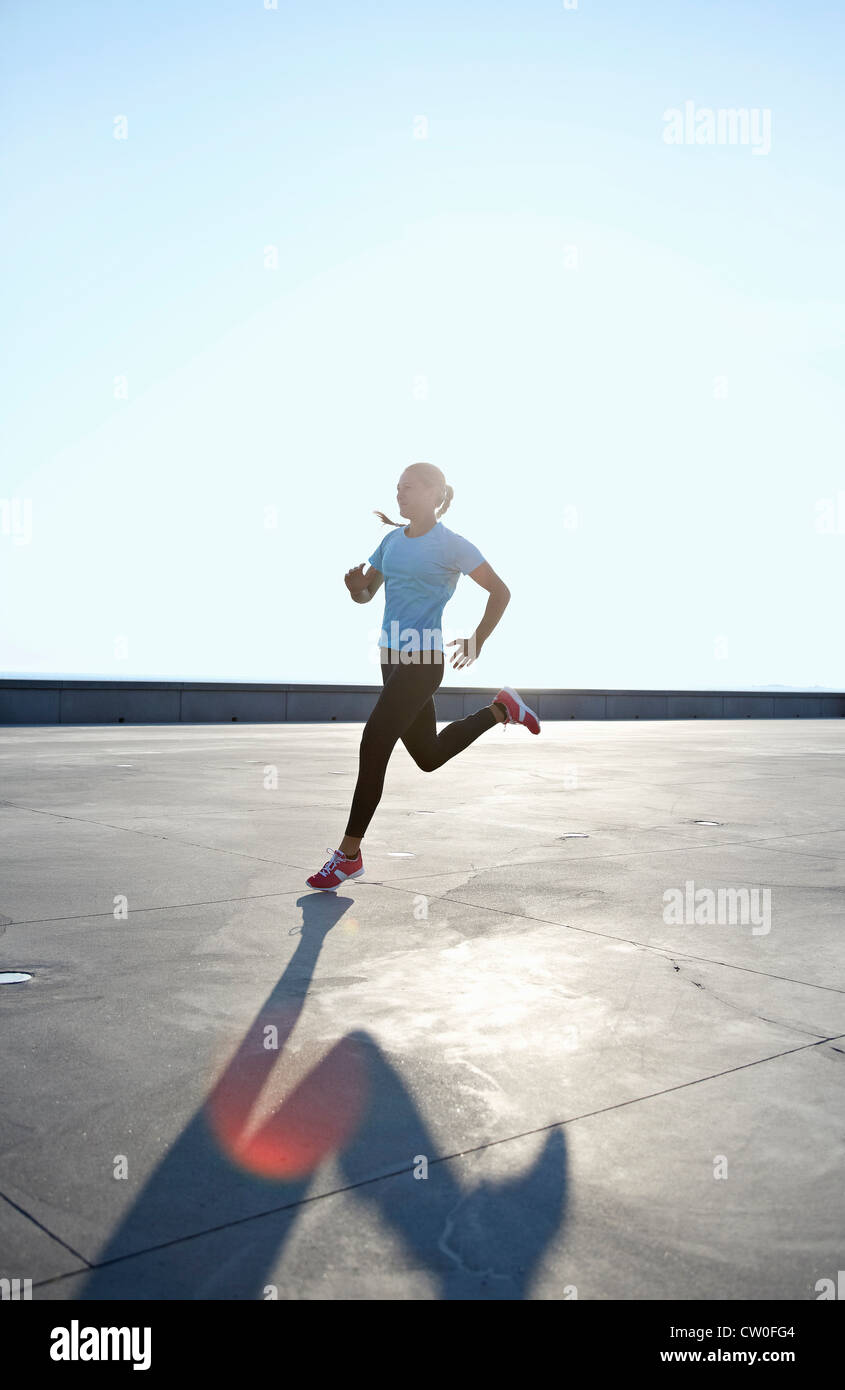 Woman running on rooftop Stock Photo