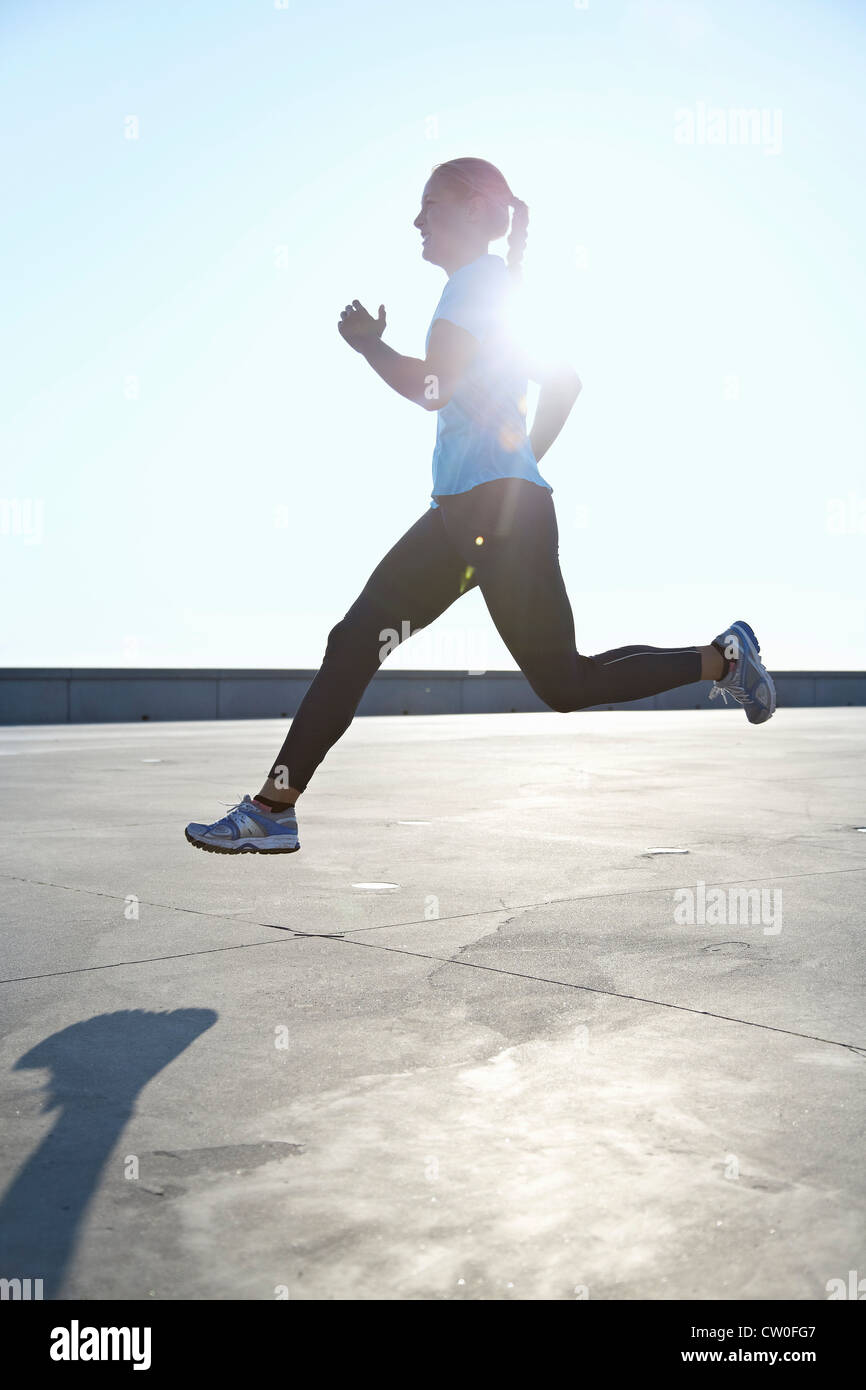 Woman running on rooftop Stock Photo