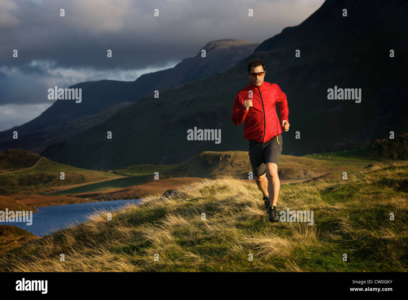 Hiker running on grassy hillside Stock Photo