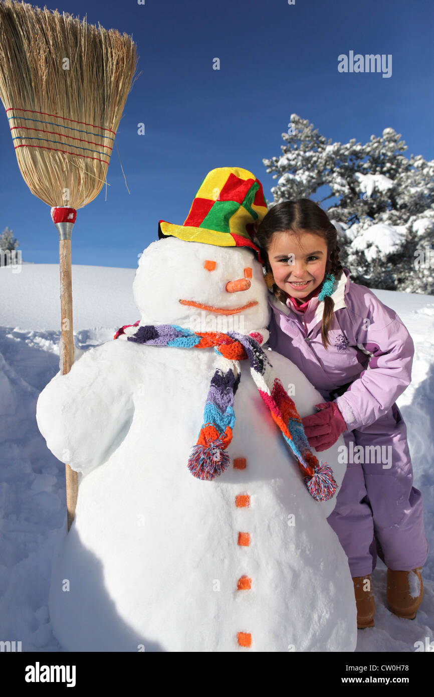 Girl next to snowman Stock Photo