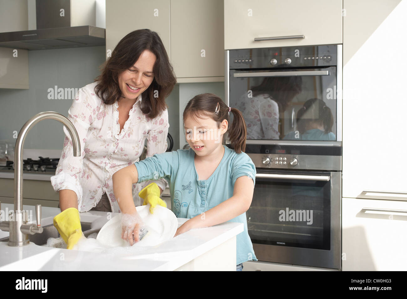 Mother and daughter washing dishes Stock Photo