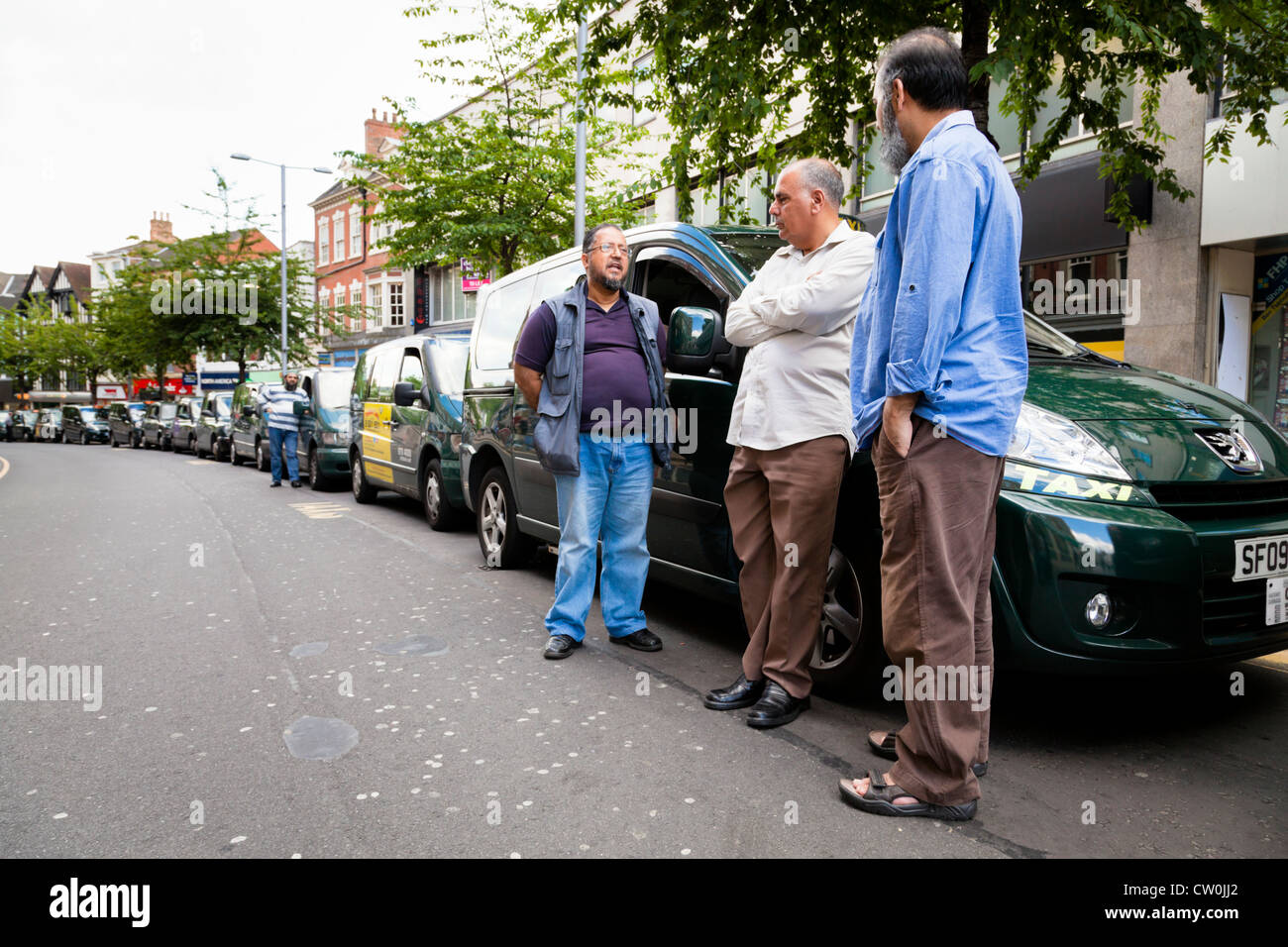 Taxi drivers standing by their cabs waiting for fares at a taxi rank in Nottingham city centre, England, UK Stock Photo