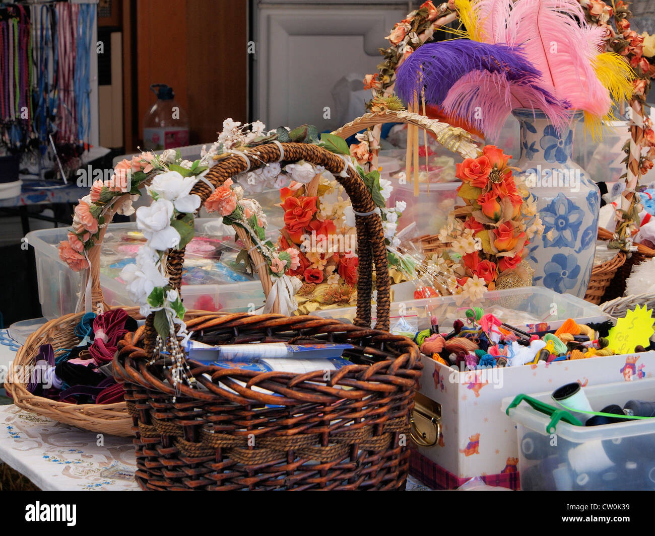 a display of embroidered silks and ribbons with cotton reels and baskets and beads Stock Photo